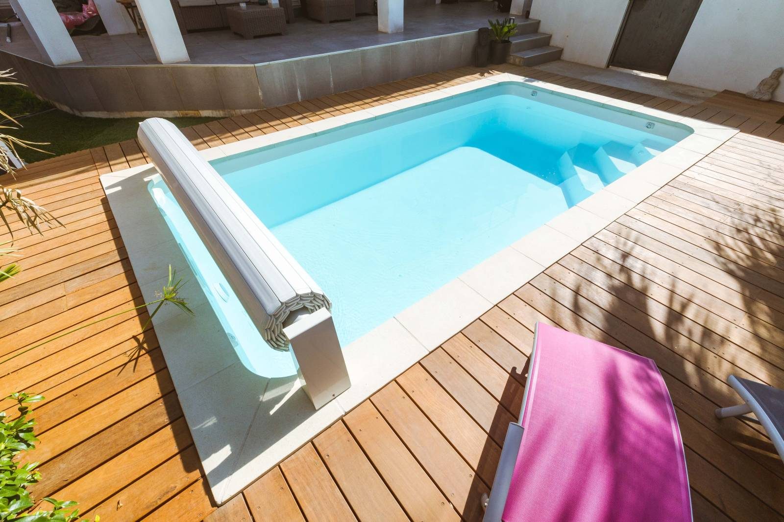 Piscine coque installée dans un jardin avec terrasse en bois